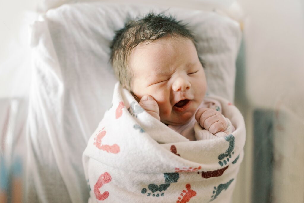 newborn baby girl wrapped in hospital blanket in bassinet yawning during fresh 48 photos 