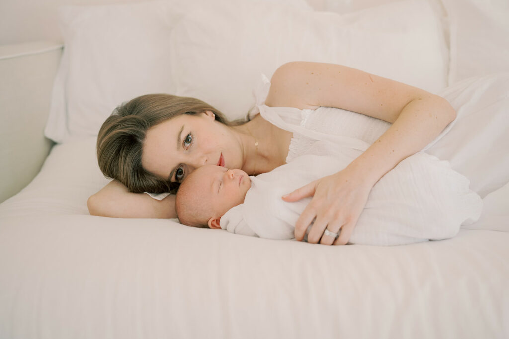 mother snuggling her newborn baby and gazing contently into camera